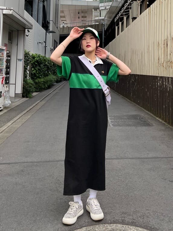 ブラック系のワンピース、パープル系のハンドバッグ、グリーン系のキャップを着用したレディースの夏コーディネートの2枚目の写真