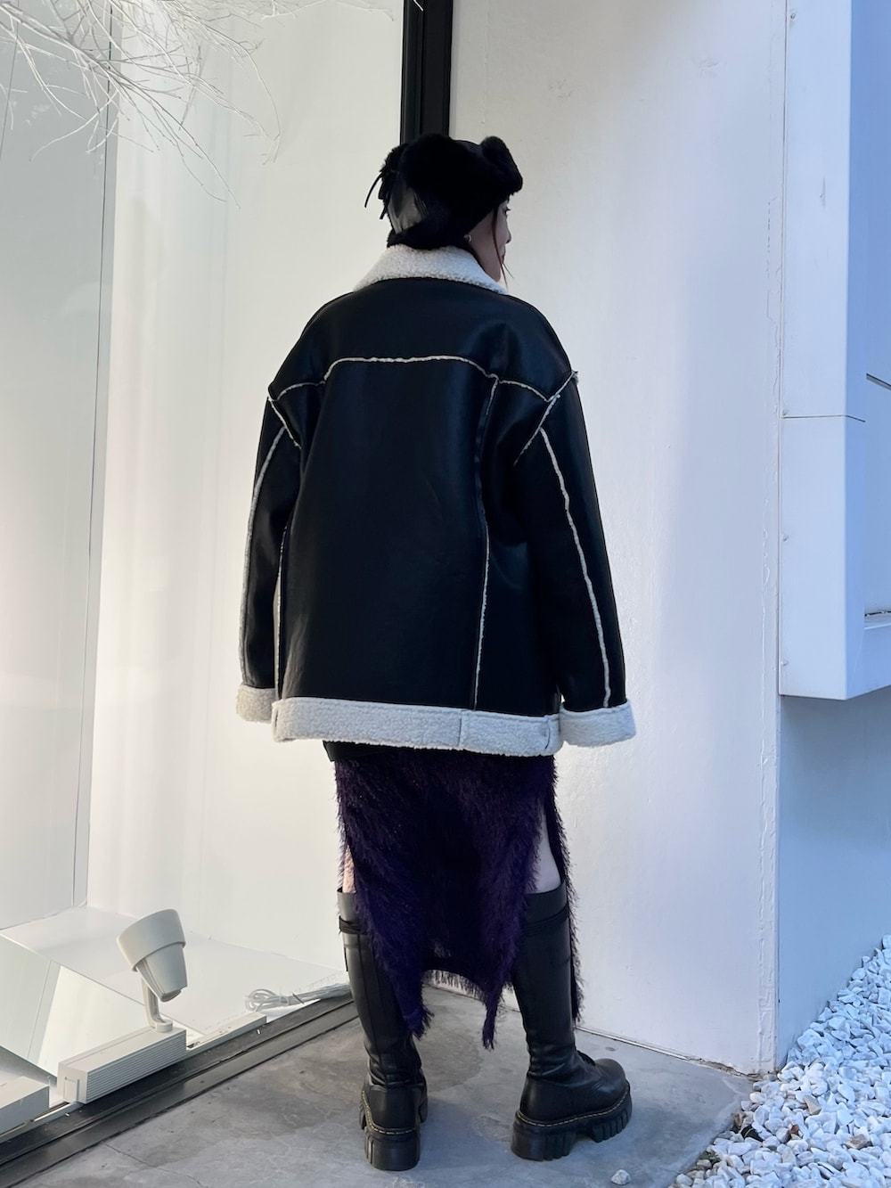 ブラック系のムートンコート、パープル系のスカート、ブラック系のスウェットを着用したレディースの夏コーディネートの3枚目の写真