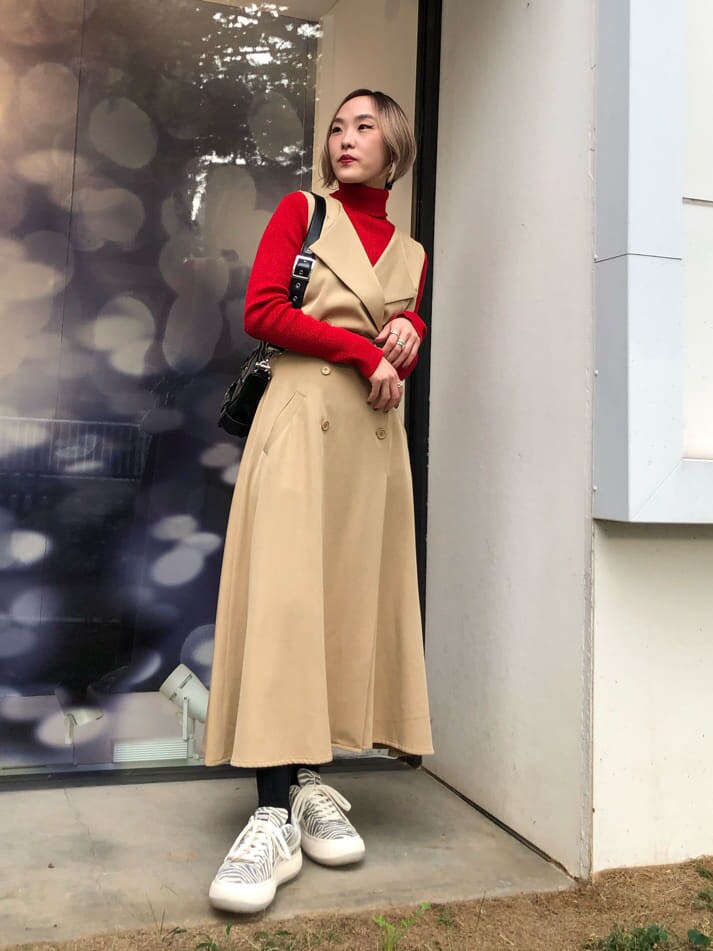 レッド系のニット/セーター、ホワイト系のスニーカー、ブラック系のショルダーバッグを着用したレディースの秋コーディネートの5枚目の写真