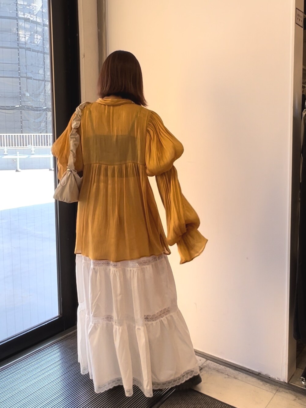 オレンジ系のシャツ/ブラウス、ホワイト系のスカート、ホワイト系のショルダーバッグを着用したレディースの春コーディネートの4枚目の写真