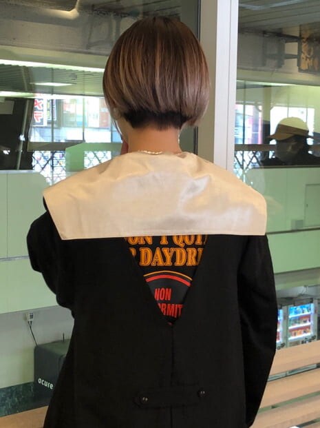 ホワイト系のシャツ/ブラウス、ブラック系のジャンパースカート、ホワイト系のブーツを着用したレディースの春コーディネートの5枚目の写真