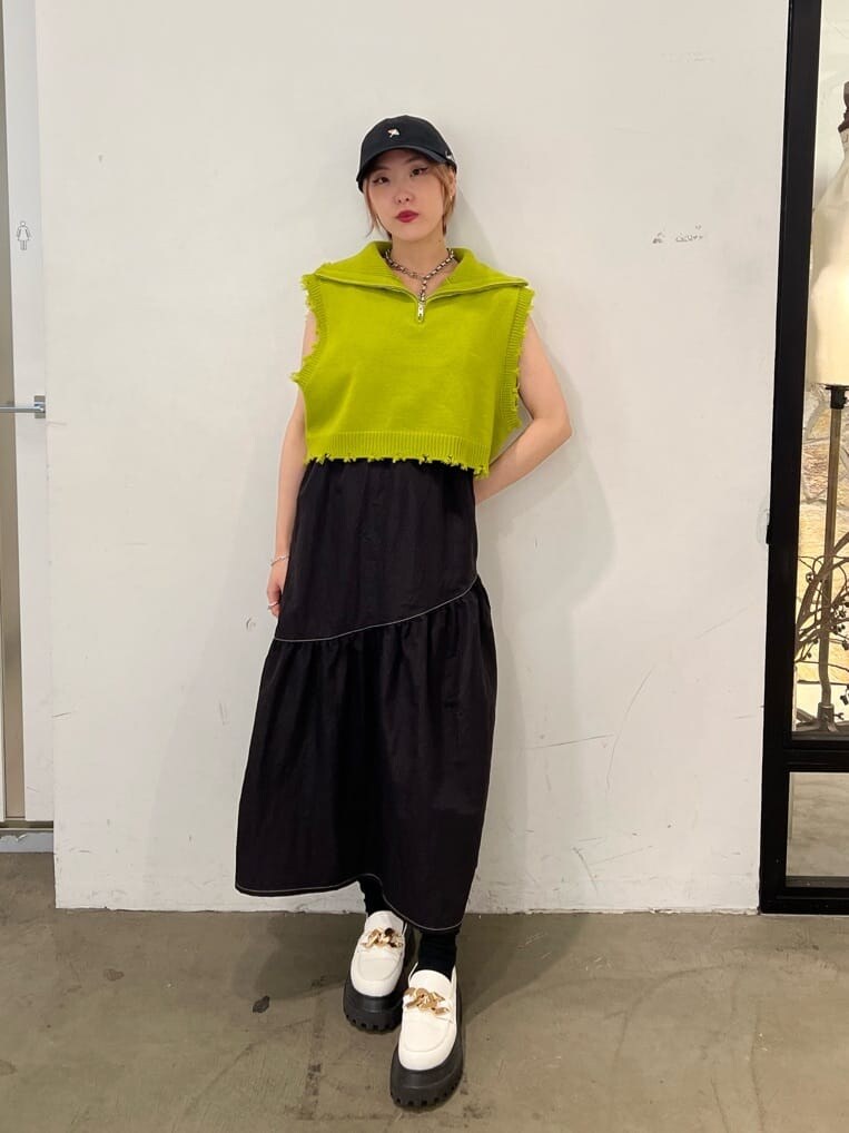 ホワイト系のローファー、グリーン系のベスト、ブラック系のジャンパースカートを着用したレディースの秋コーディネートの6枚目の写真