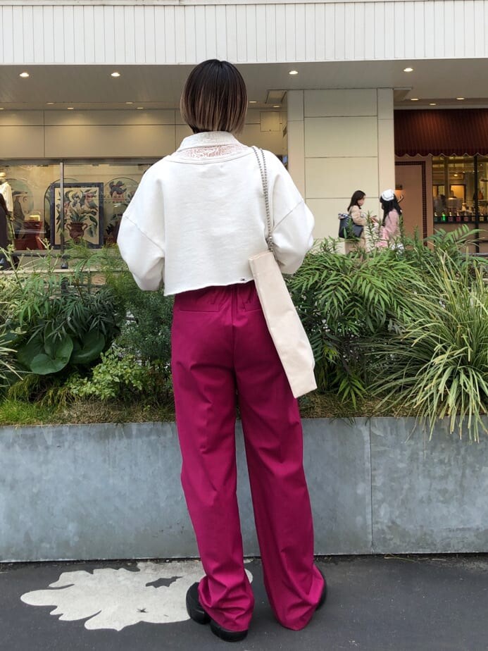 ピンク系のスラックス、ホワイト系のトートバッグ、ブラック系のブーツを着用したレディースの春コーディネートの5枚目の写真