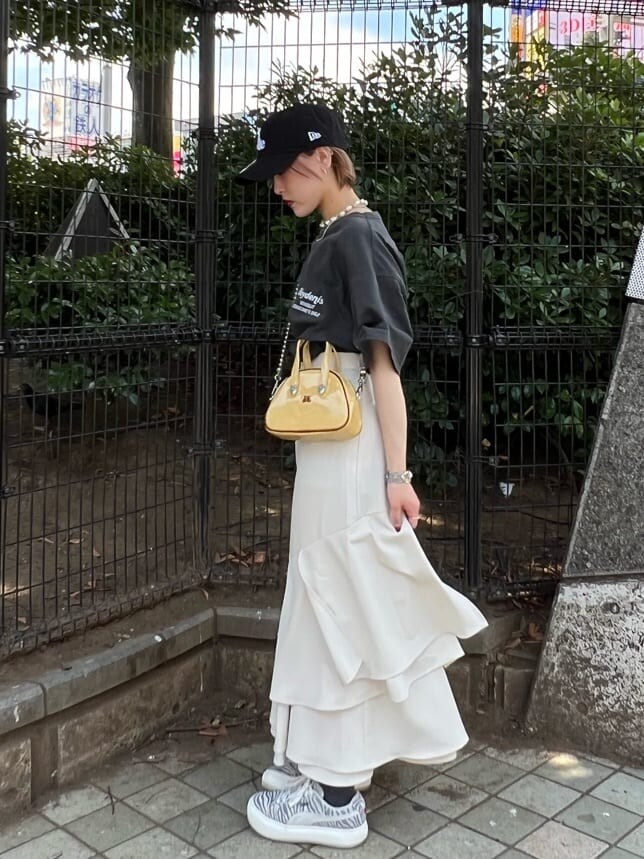 ホワイト系のスカート、イエロー系のボストンバッグ、ブラック系のTシャツ/カットソーを着用したレディースの夏コーディネートの2枚目の写真