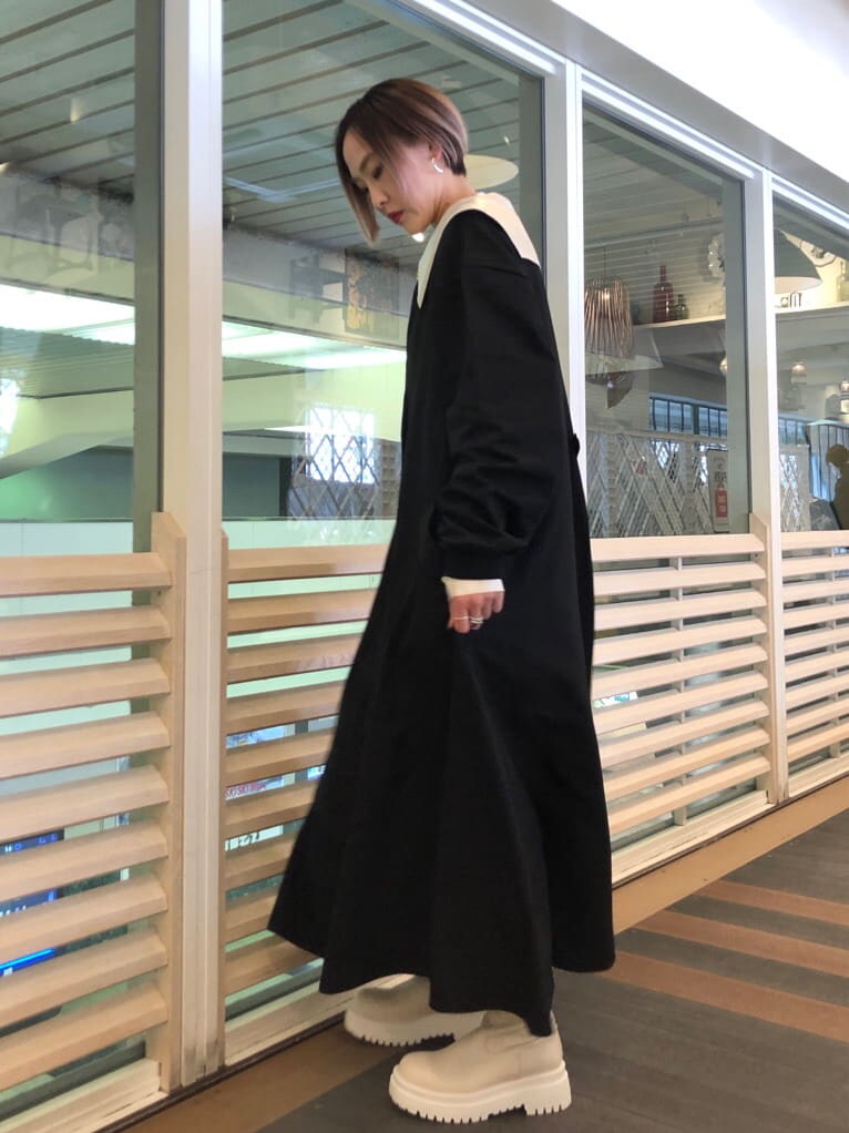 ホワイト系のシャツ/ブラウス、ブラック系のジャンパースカート、ホワイト系のブーツを着用したレディースの春コーディネートの2枚目の写真