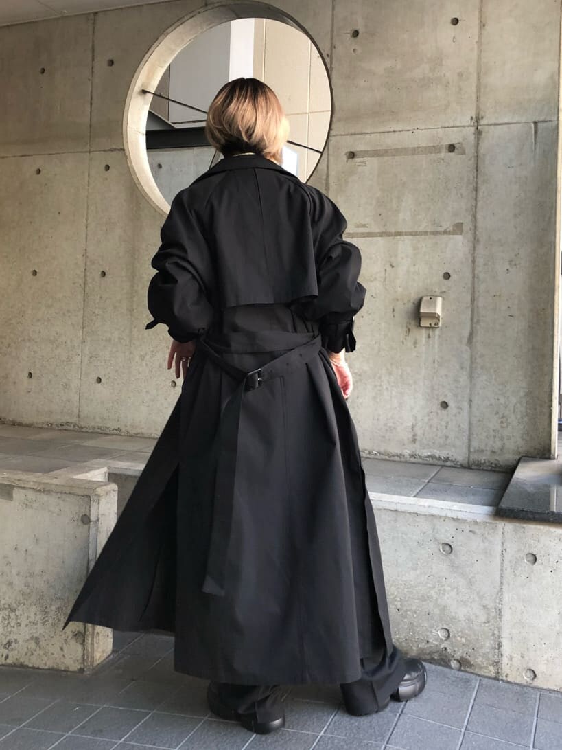 ブラック系のトレンチコート、グリーン系のシャツ/ブラウス、ブラック系のスラックスを着用したレディースの春コーディネートの2枚目の写真