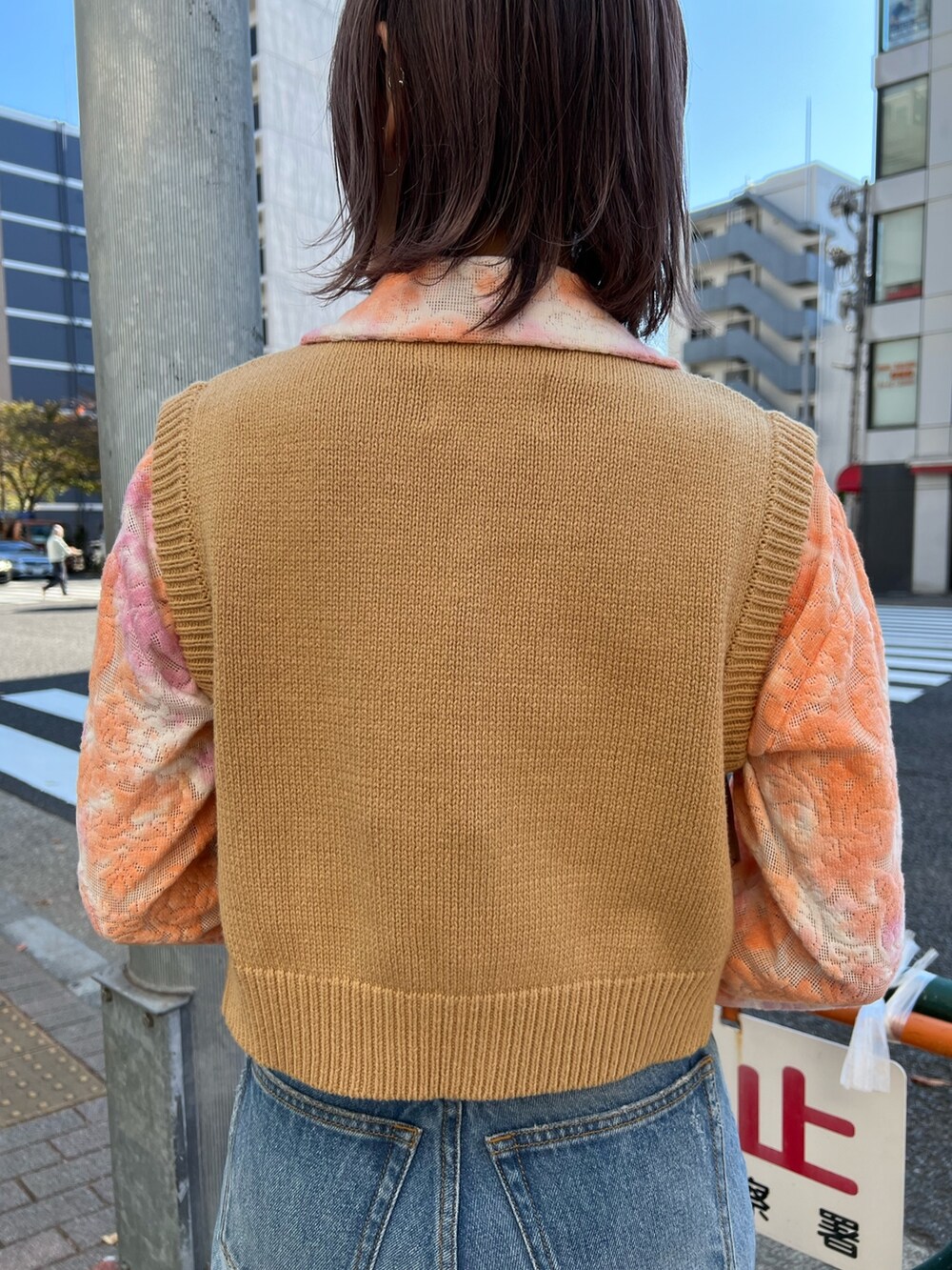 オレンジ系のシャツ/ブラウス、ベージュ系のベスト、ブルー系のデニムパンツを着用したレディースの春コーディネートの8枚目の写真