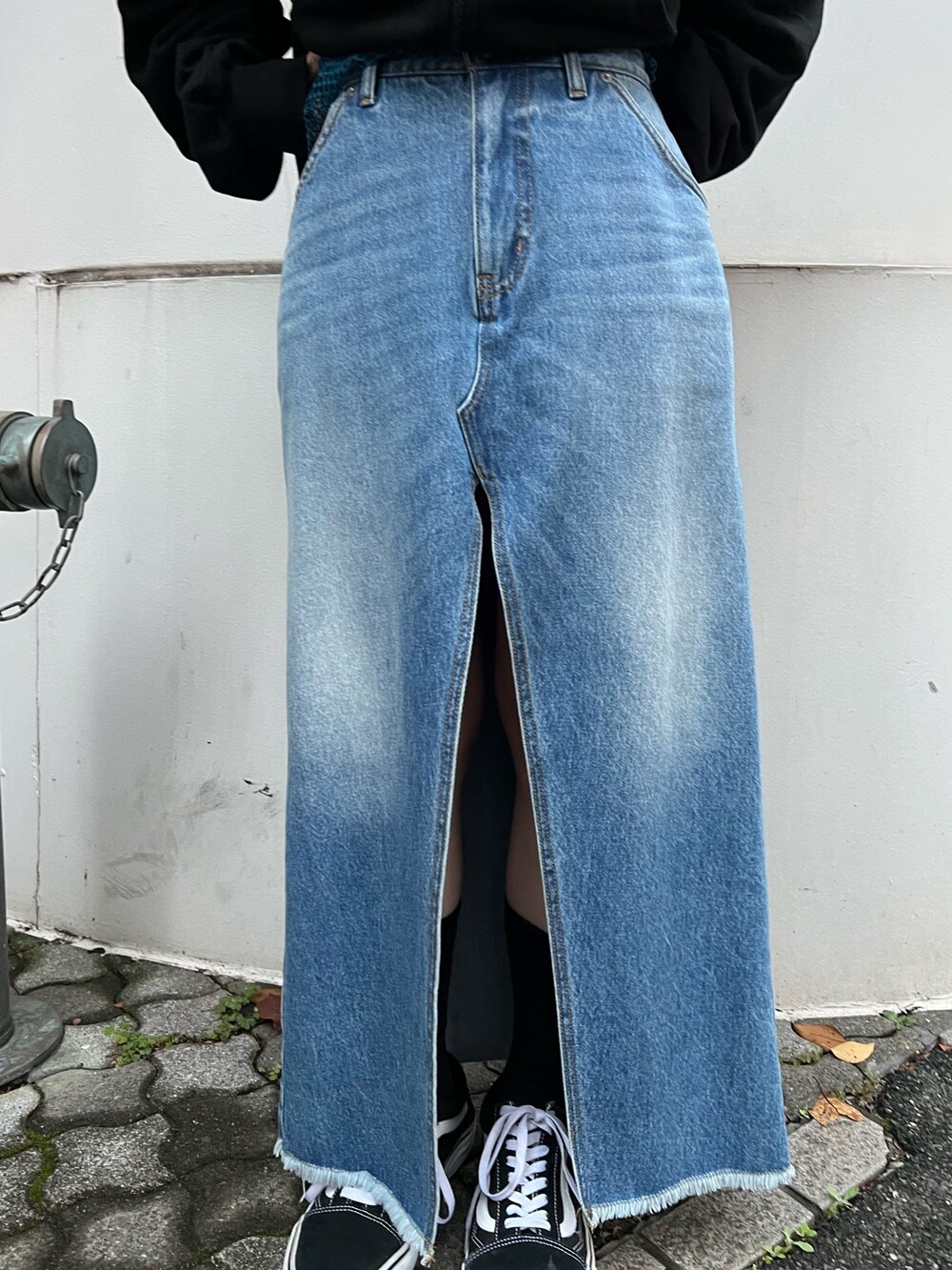 ブルー系のスカート、ブラック系のパーカー、ブルー系のタンクトップを着用したレディースの春コーディネートの8枚目の写真