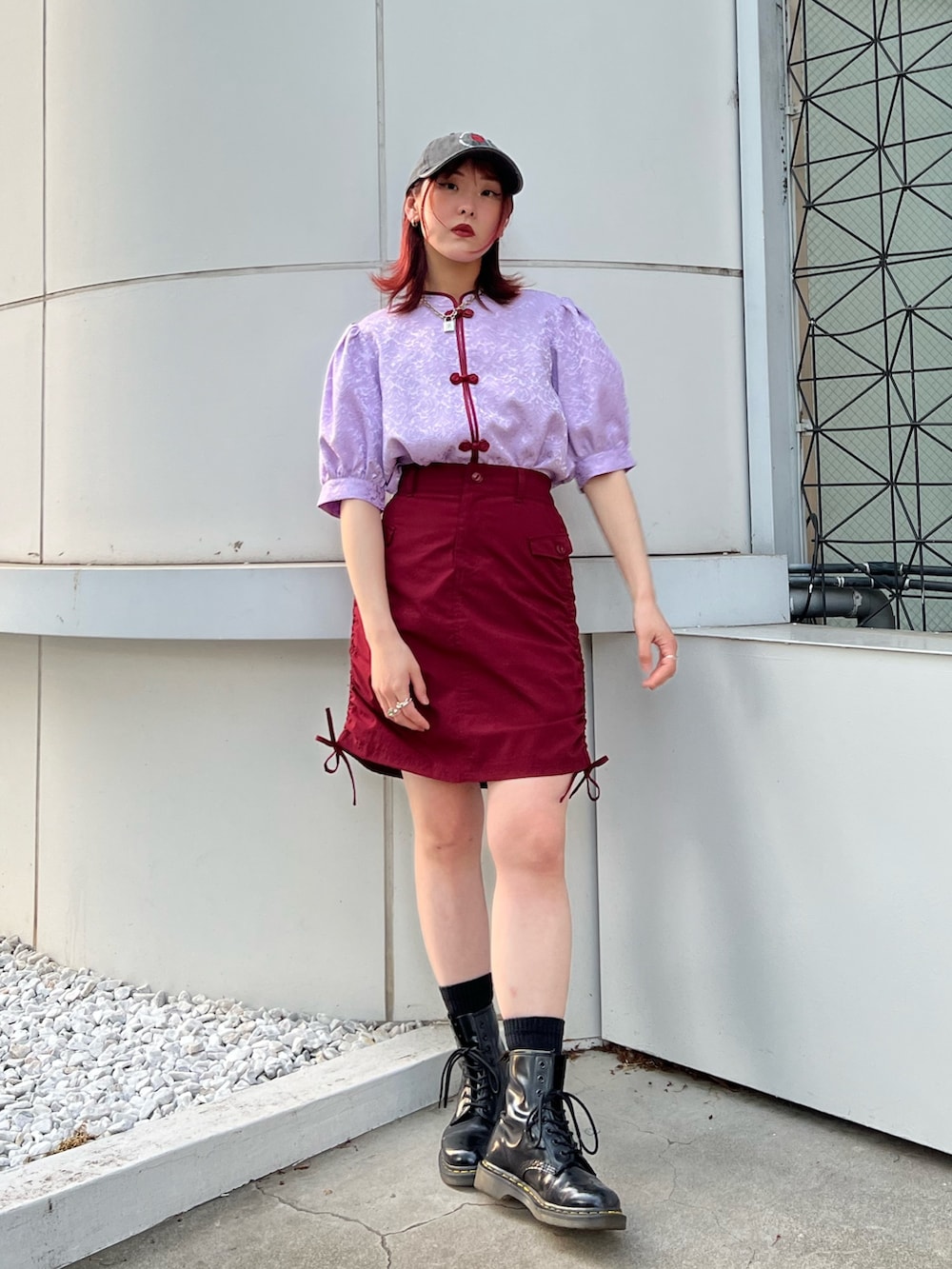 パープル系のシャツ/ブラウス、レッド系のスカート、ブラック系のキャップを着用したレディースの春コーディネートの2枚目の写真
