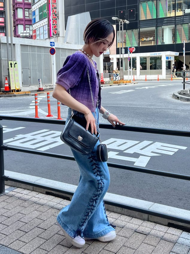 ブラック系のハンドバッグ、ブラック系のニット/セーター、ブルー系のデニムパンツを着用したレディースの夏コーディネートの2枚目の写真