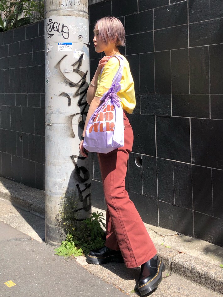 パープル系のトートバッグ、ブラウン系のデニムパンツ、イエロー系のTシャツ/カットソーを着用したレディースの春コーディネートの2枚目の写真