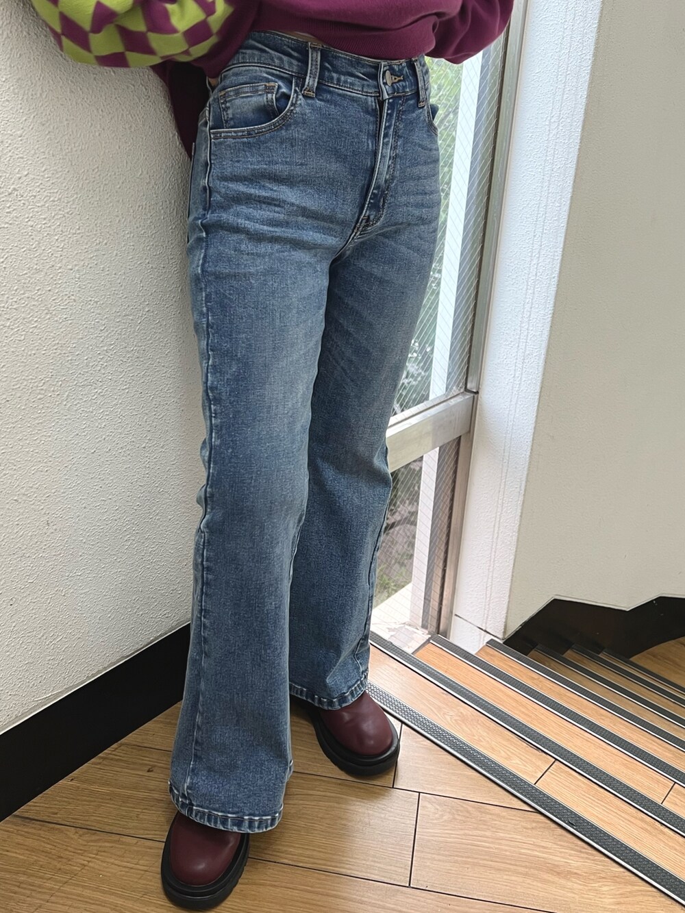パープル系のニット/セーター、ブルー系のデニムパンツ、レッド系のブーツを着用したレディースの秋コーディネートの9枚目の写真