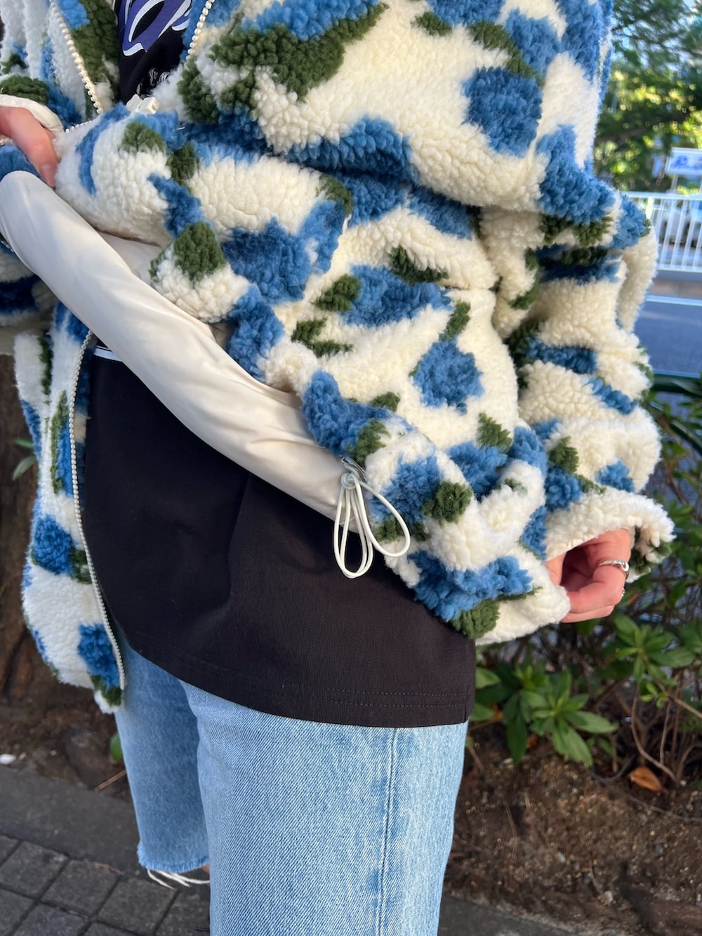 ホワイト系のブルゾン、ブラック系のTシャツ/カットソー、ブラック系のブーツを着用したレディースの秋コーディネートの6枚目の写真