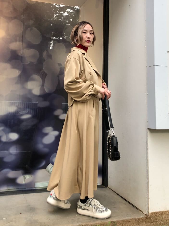 レッド系のニット/セーター、ホワイト系のスニーカー、ブラック系のショルダーバッグを着用したレディースの秋コーディネートの2枚目の写真