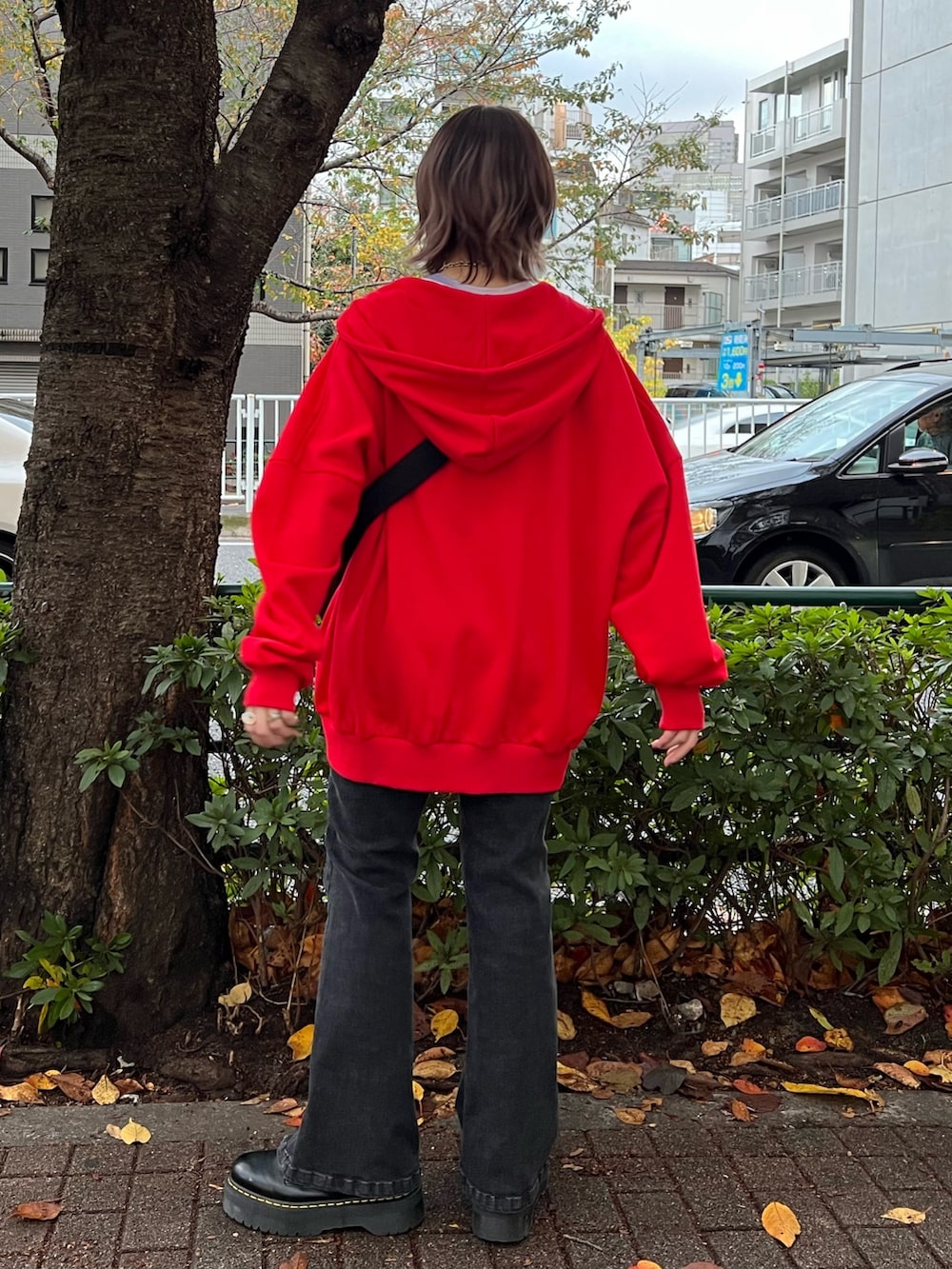 レッド系のパーカー、パープル系のTシャツ/カットソー、ブラック系のデニムパンツを着用したレディースの春コーディネートの3枚目の写真