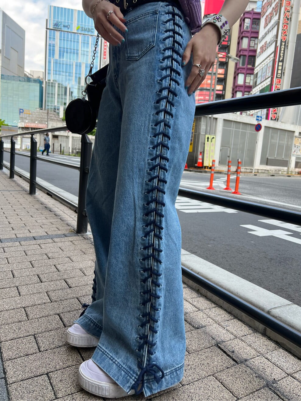 ブラック系のハンドバッグ、ブラック系のニット/セーター、ブルー系のデニムパンツを着用したレディースの夏コーディネートの8枚目の写真