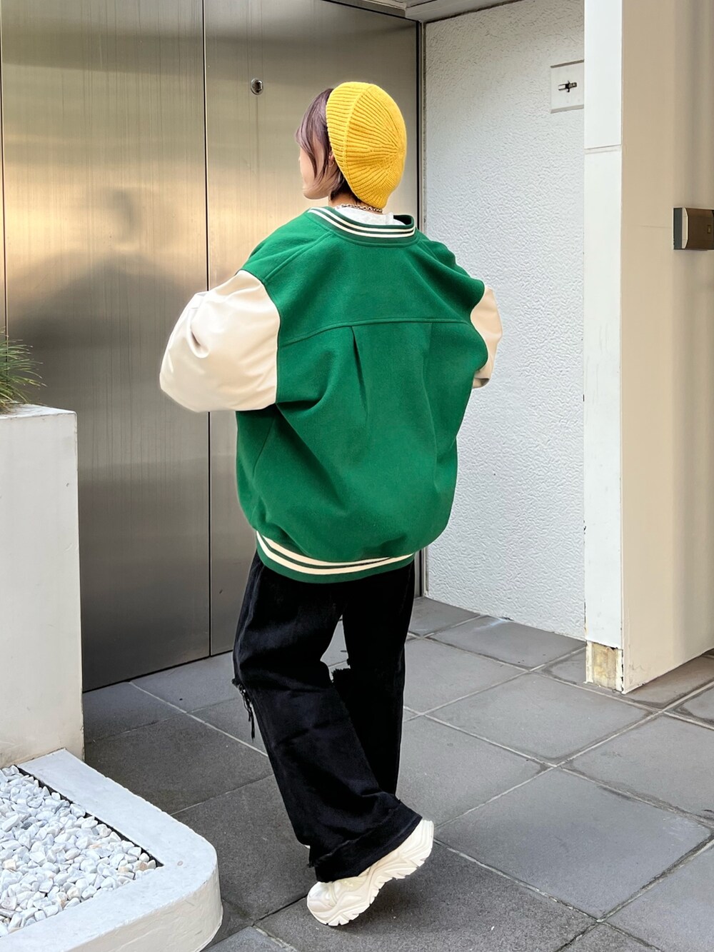 グレー系のスウェット、グリーン系のスタジャン、ホワイト系のスニーカーを着用したレディースの秋コーディネートの2枚目の写真