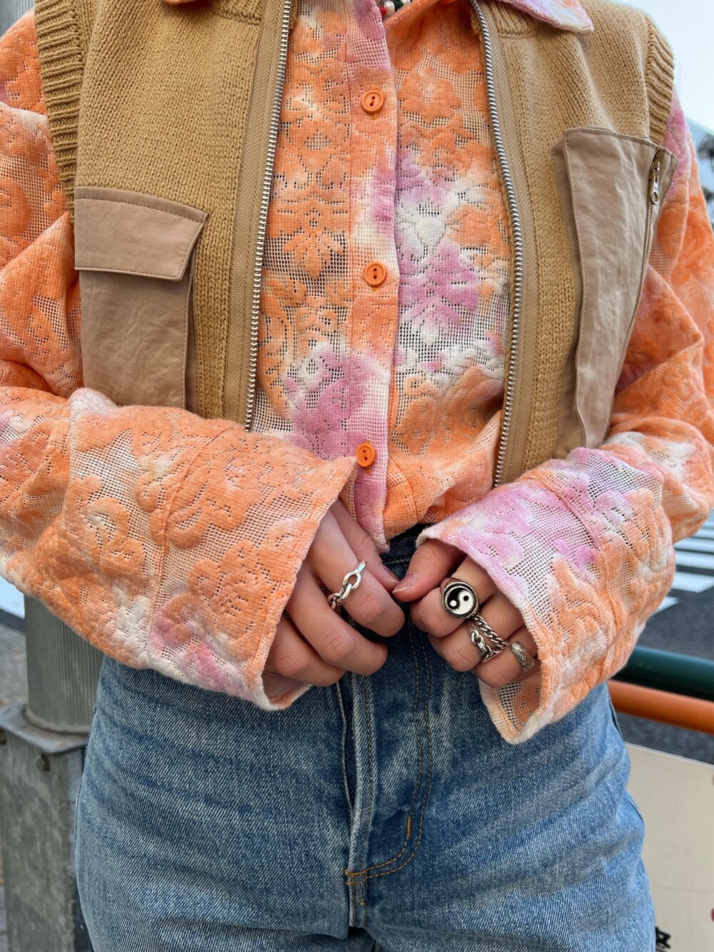 オレンジ系のシャツ/ブラウス、ベージュ系のベスト、ブルー系のデニムパンツを着用したレディースの春コーディネートの9枚目の写真