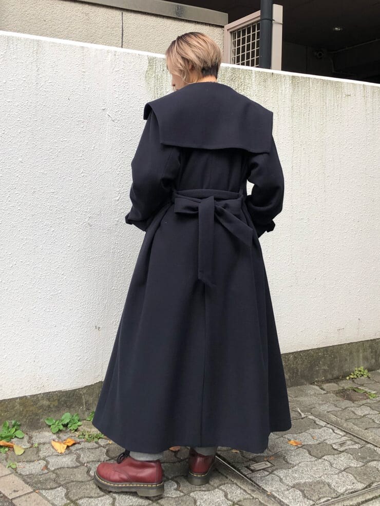 ブルー系のチェスターコート、ブラック系のデニムパンツ、ブラック系のニット/セーターを着用したレディースの秋コーディネートの3枚目の写真