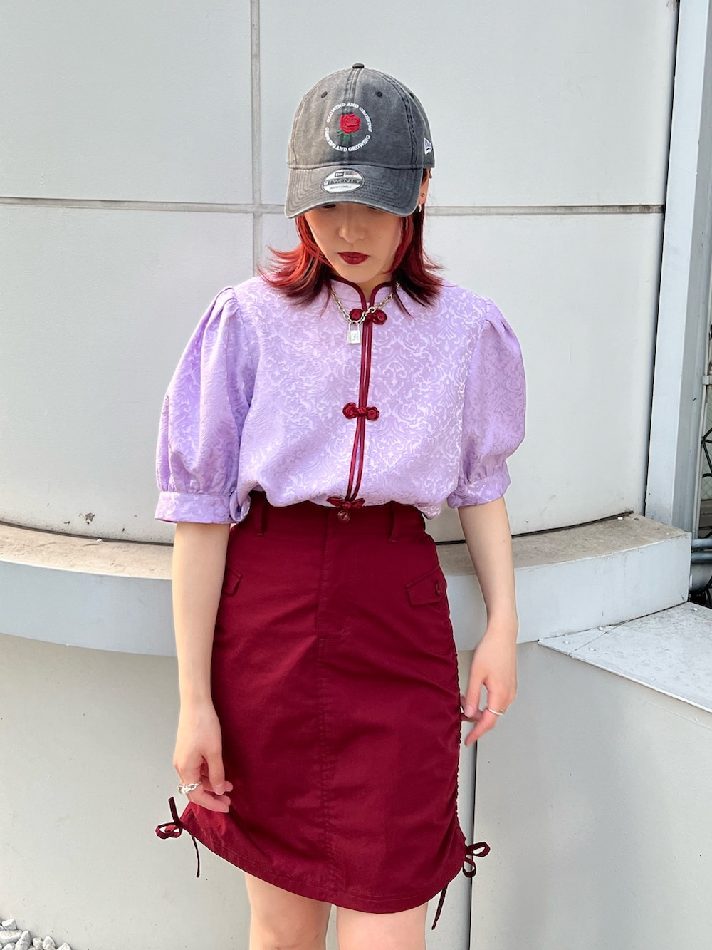 パープル系のシャツ/ブラウス、レッド系のスカート、ブラック系のキャップを着用したレディースの春コーディネートの6枚目の写真