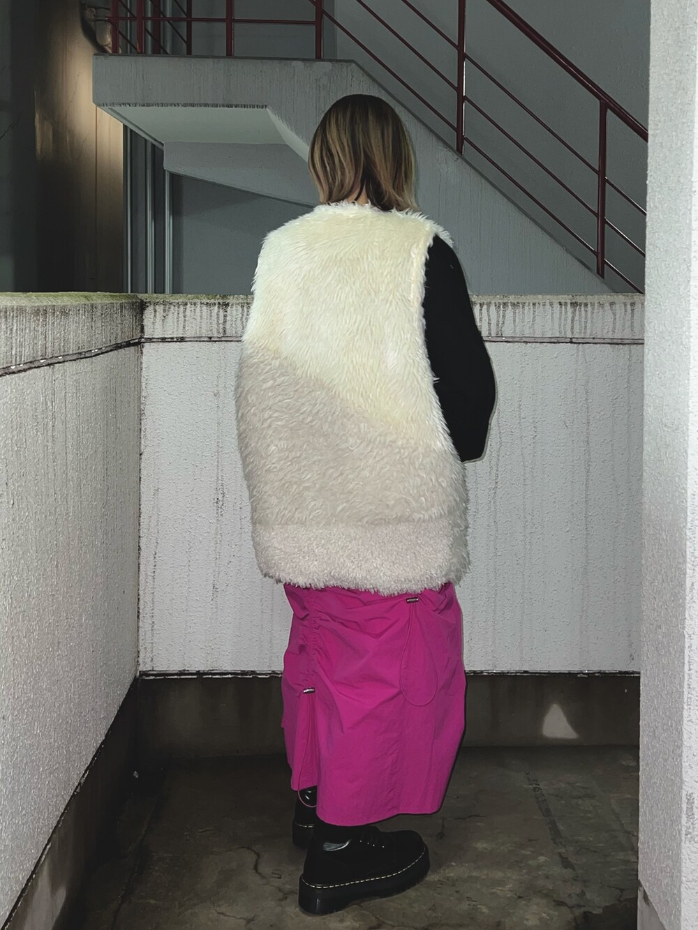 ブラック系のスウェット、ホワイト系のベスト、ピンク系のスカートを着用したレディースの冬コーディネートの3枚目の写真