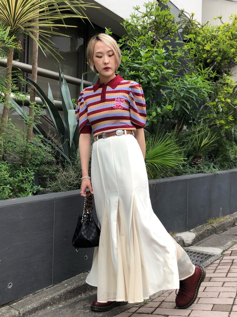 レッド系のニット/セーター、ホワイト系のスカート、ブラック系のショルダーバッグを着用したレディースの夏コーディネートの3枚目の写真