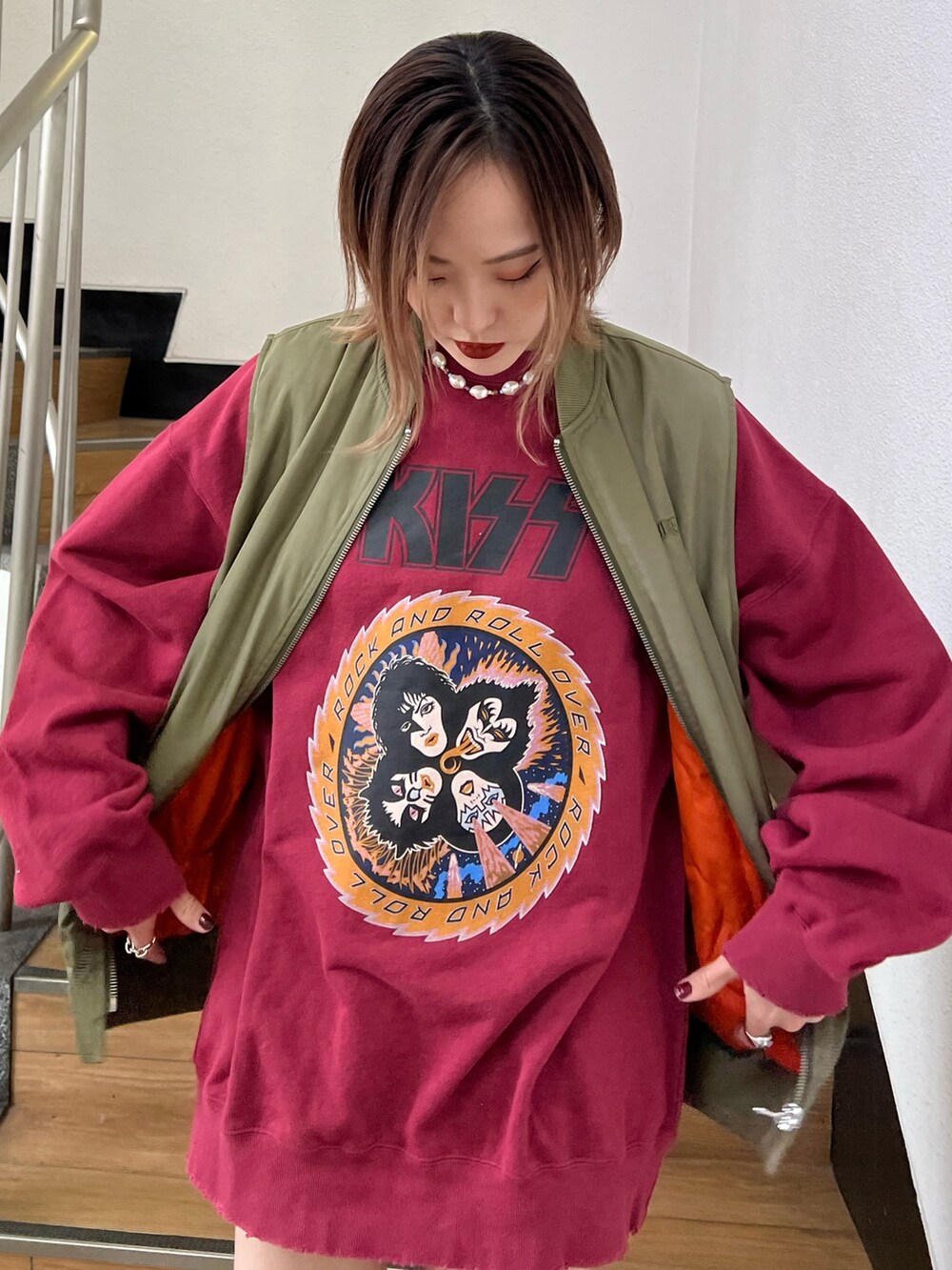 レッド系のスウェット、グリーン系のMA-1、ブラック系のデニムパンツを着用したレディースの冬コーディネートの5枚目の写真