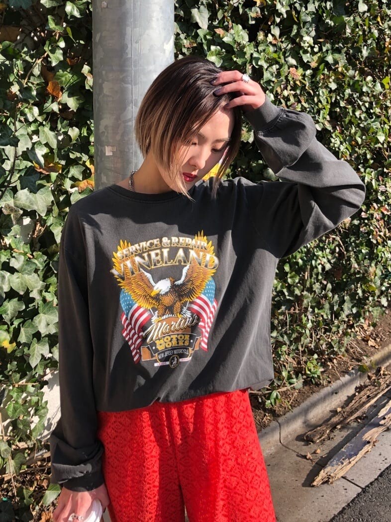 オレンジ系のスラックス、ブラック系のTシャツ/カットソーを着用したレディースの春コーディネートの6枚目の写真