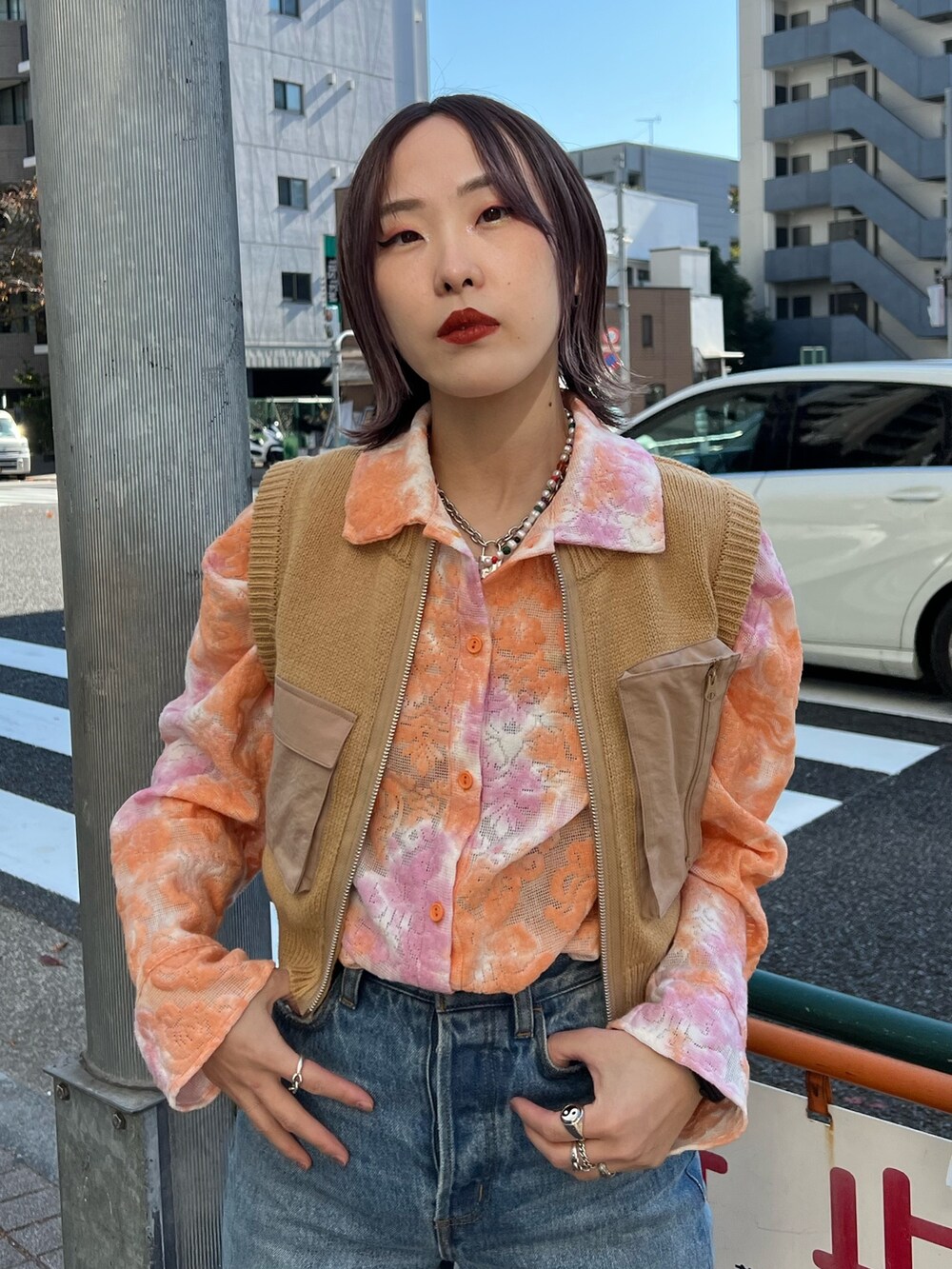 オレンジ系のシャツ/ブラウス、ベージュ系のベスト、ブルー系のデニムパンツを着用したレディースの春コーディネートの6枚目の写真