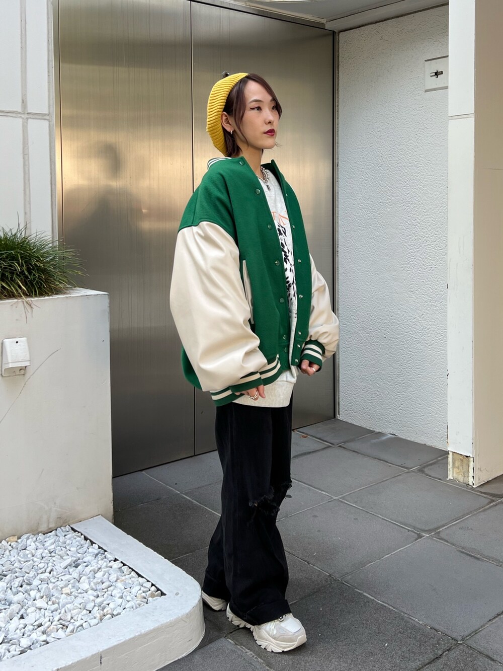 グレー系のスウェット、グリーン系のスタジャン、ホワイト系のスニーカーを着用したレディースの秋コーディネートの4枚目の写真