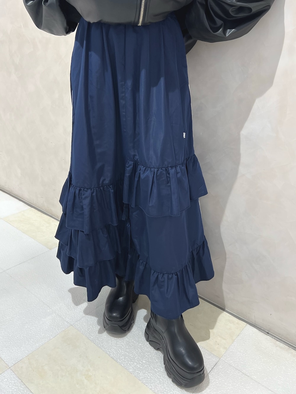 ブラック系のブルゾン、ブルー系のスカート、ブラック系のブーツを着用したレディースの秋コーディネートの9枚目の写真