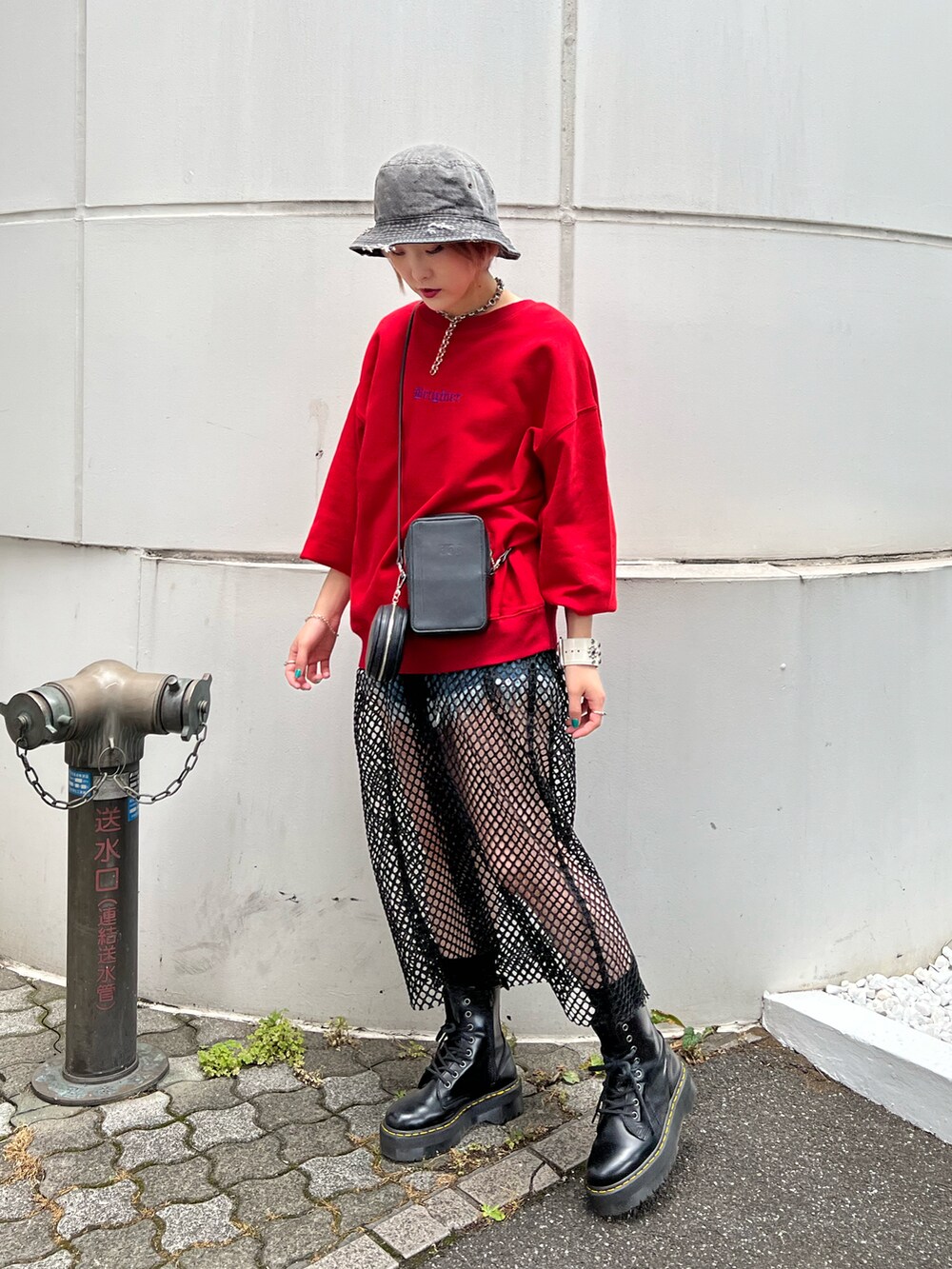 レッド系のスウェット、ブルー系のデニムパンツ、ブラック系のブーツを着用したレディースの秋コーディネートの2枚目の写真