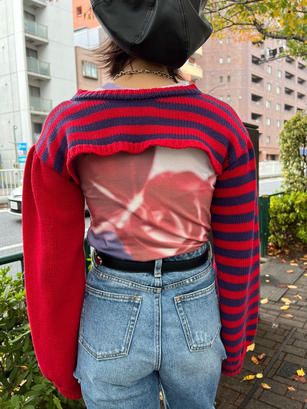 レッド系のニット/セーター、パープル系のTシャツ/カットソー、ブルー系のデニムパンツを着用したレディースの冬コーディネートの8枚目の写真