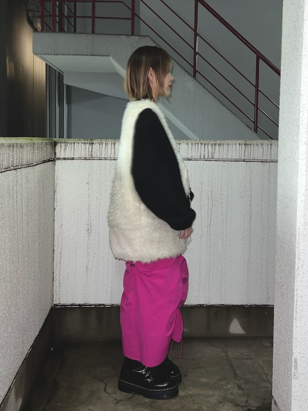 ブラック系のスウェット、ホワイト系のベスト、ピンク系のスカートを着用したレディースの冬コーディネートの2枚目の写真