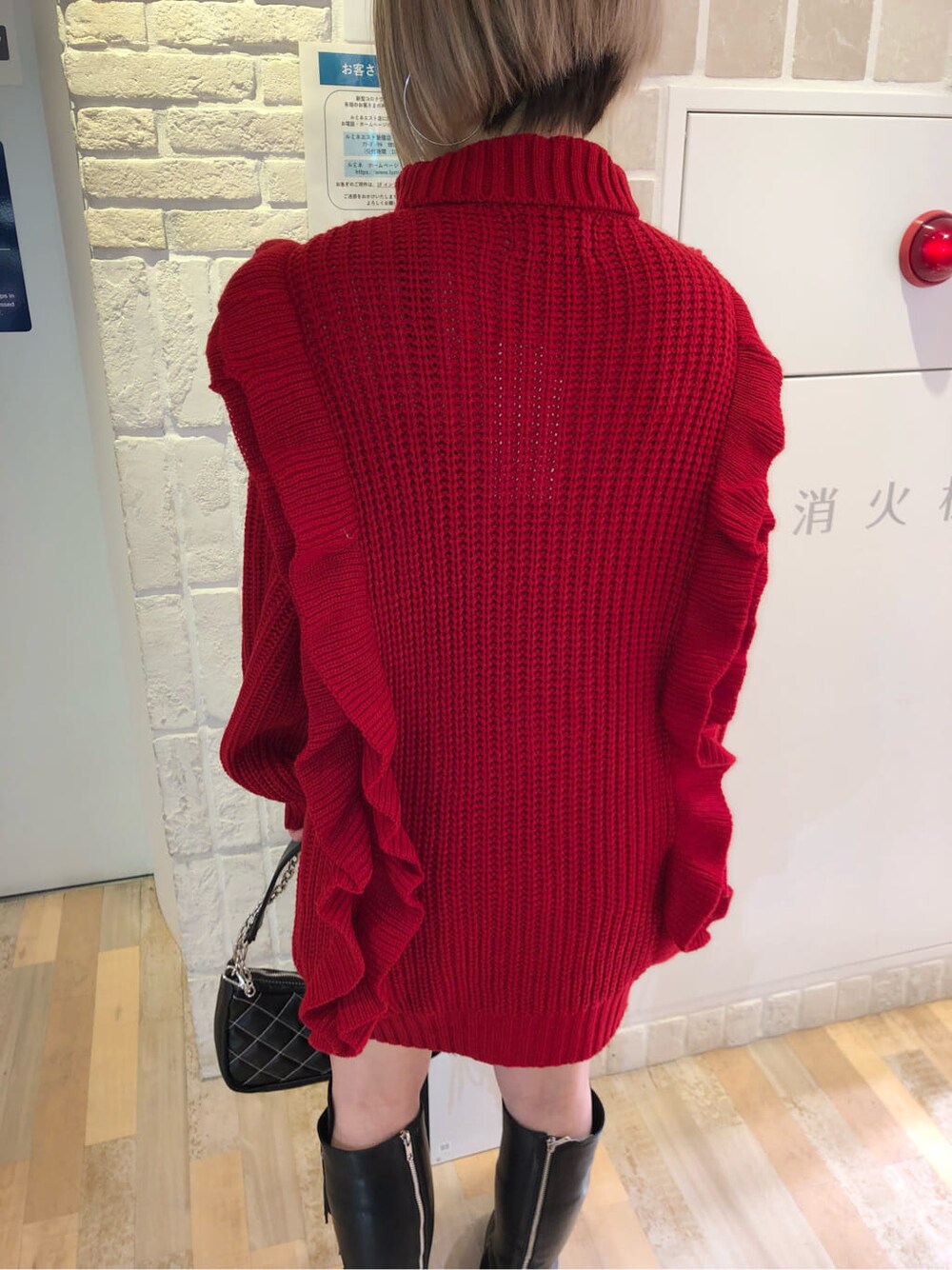 ブラック系のチェスターコート、レッド系のニット/セーター、ブラック系のブーツを着用したレディースの冬コーディネートの9枚目の写真