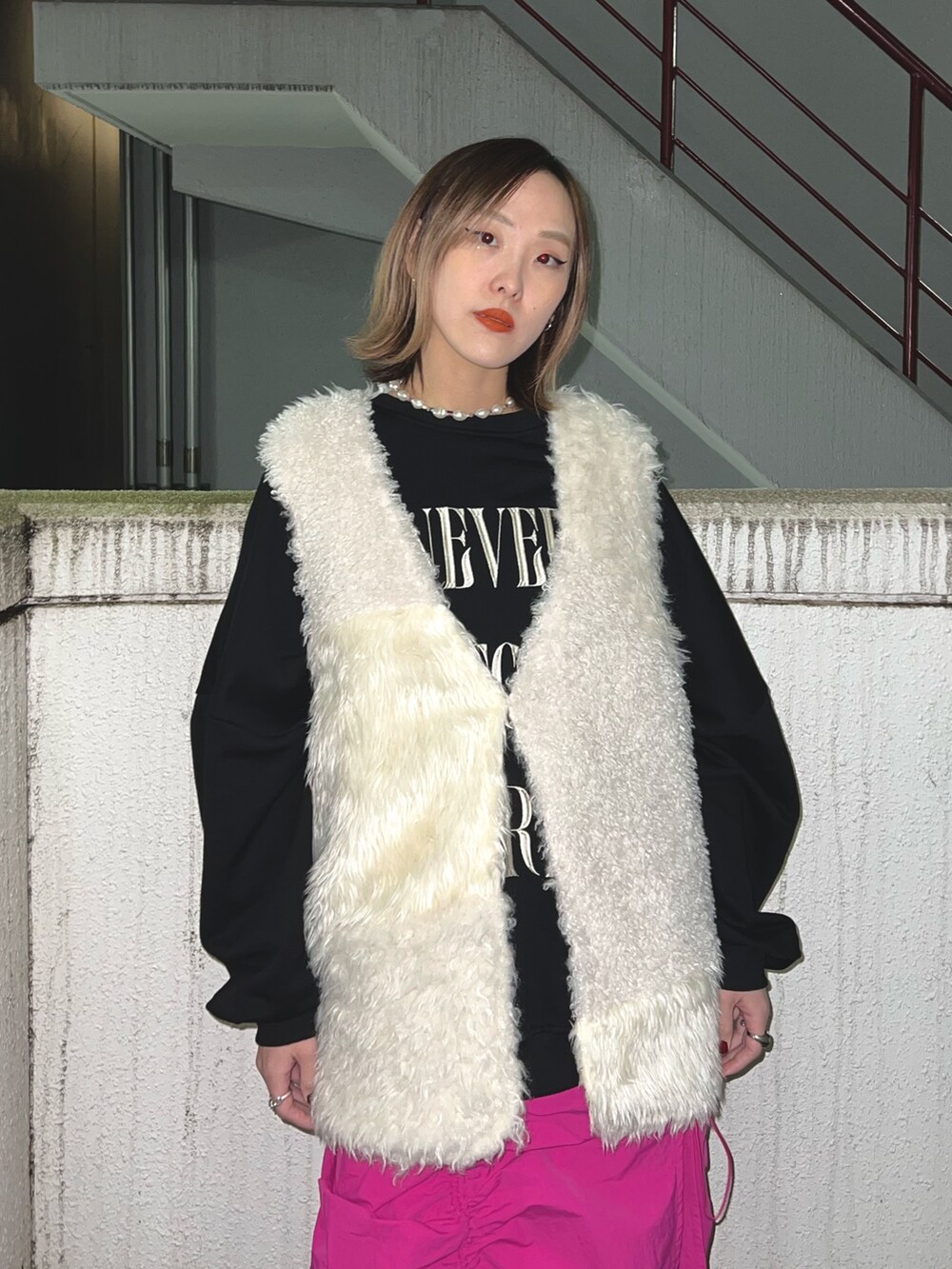 ブラック系のスウェット、ホワイト系のベスト、ピンク系のスカートを着用したレディースの冬コーディネートの6枚目の写真