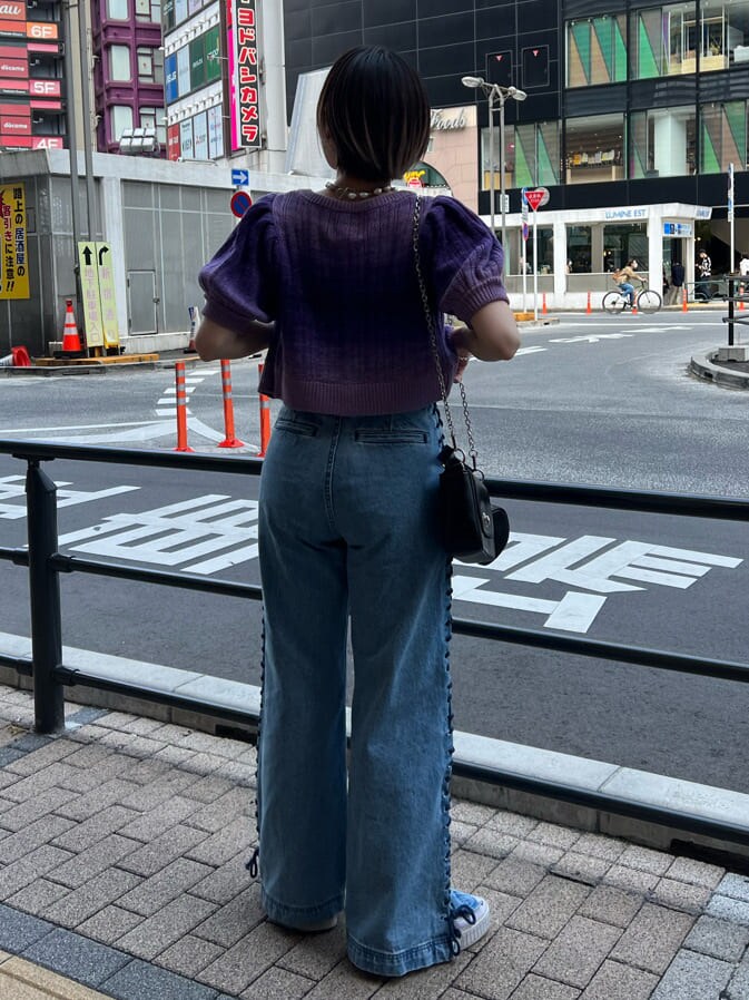 ブラック系のハンドバッグ、ブラック系のニット/セーター、ブルー系のデニムパンツを着用したレディースの夏コーディネートの3枚目の写真