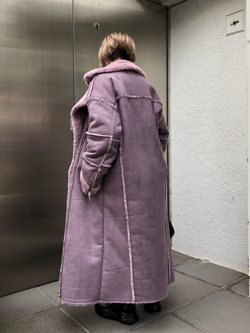 パープル系のムートンコート、ブラック系のその他パンツ、ブラック系のブーツを着用したレディースの秋コーディネートの3枚目の写真