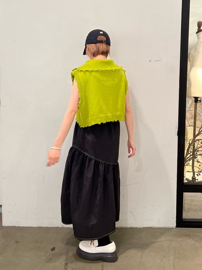 ホワイト系のローファー、グリーン系のベスト、ブラック系のジャンパースカートを着用したレディースの秋コーディネートの5枚目の写真