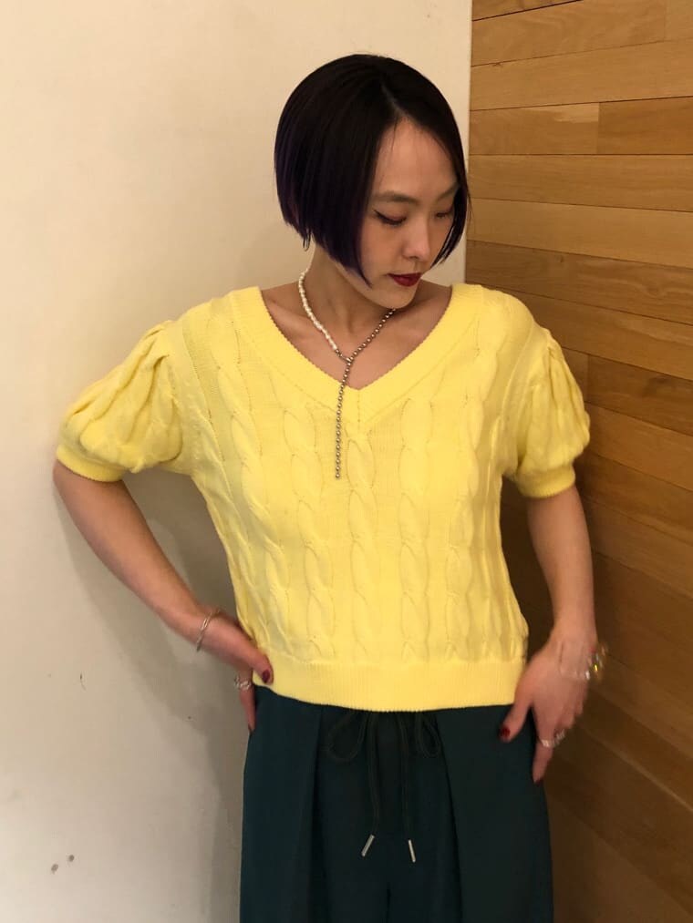 グリーン系のスラックス、イエロー系のニット/セーター、シルバー系のネックレスを着用したレディースの冬コーディネートの5枚目の写真