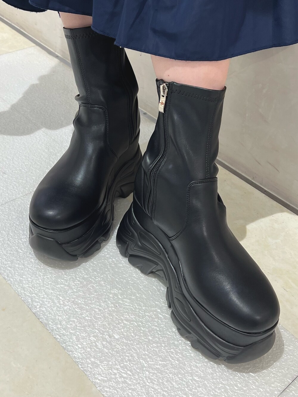 ブラック系のブルゾン、ブルー系のスカート、ブラック系のブーツを着用したレディースの秋コーディネートの10枚目の写真