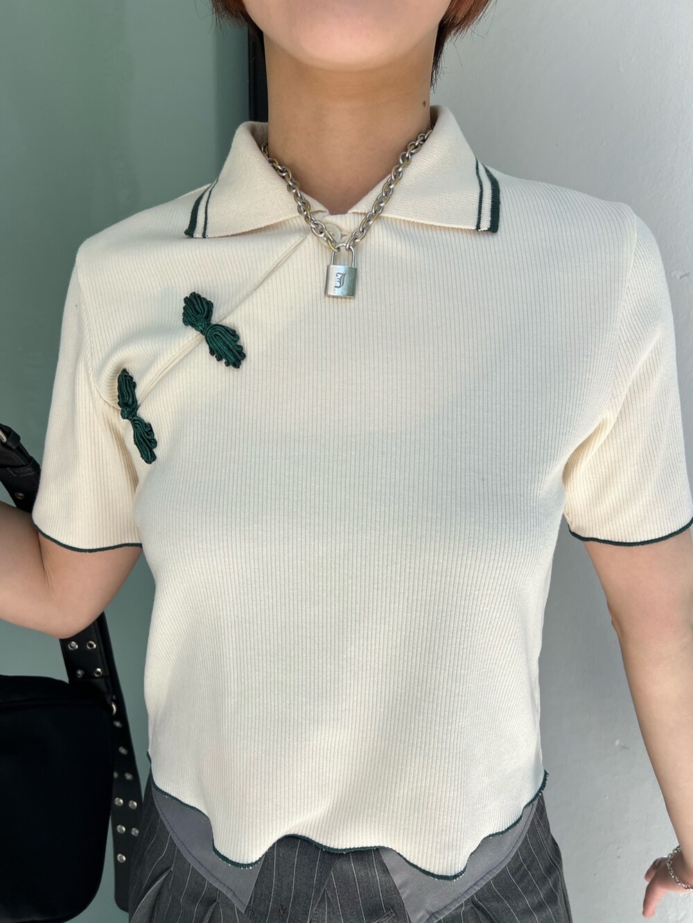 ホワイト系のポロシャツ、グレー系のスラックス、ブラック系のショルダーバッグを着用したレディースの夏コーディネートの6枚目の写真