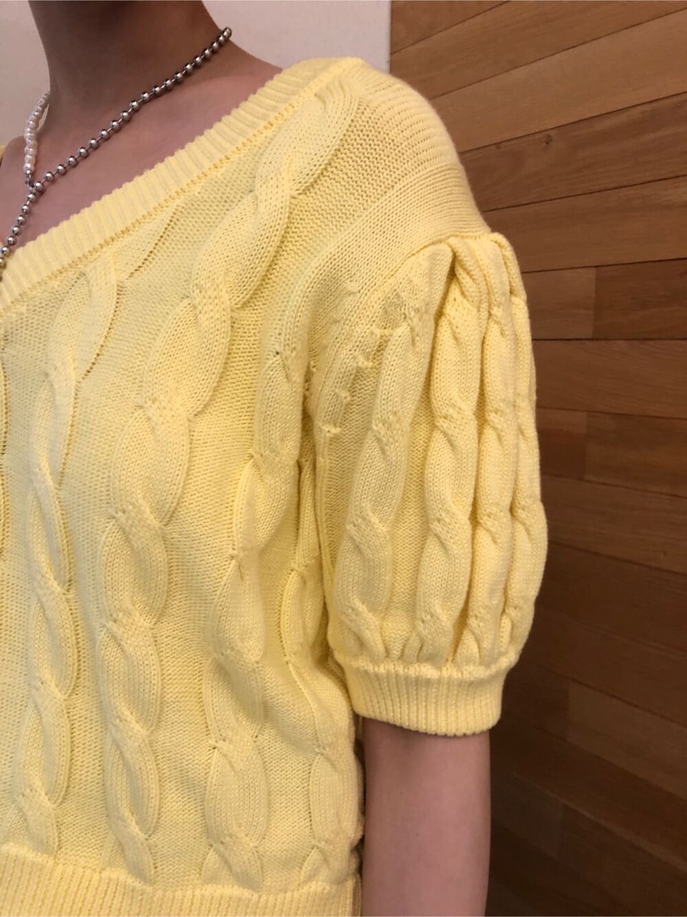 グリーン系のスラックス、イエロー系のニット/セーター、シルバー系のネックレスを着用したレディースの冬コーディネートの7枚目の写真