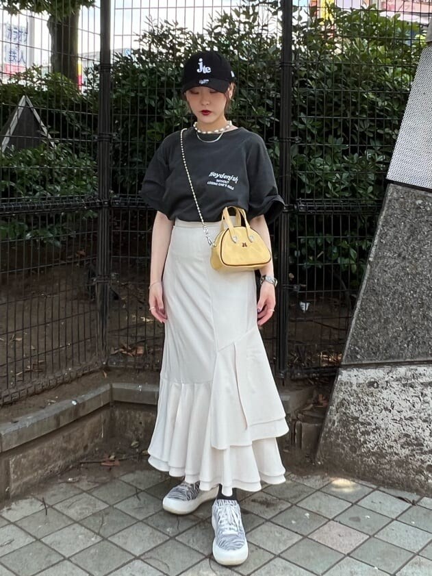 ホワイト系のスカート、イエロー系のボストンバッグ、ブラック系のTシャツ/カットソーを着用したレディースの夏コーディネートの5枚目の写真