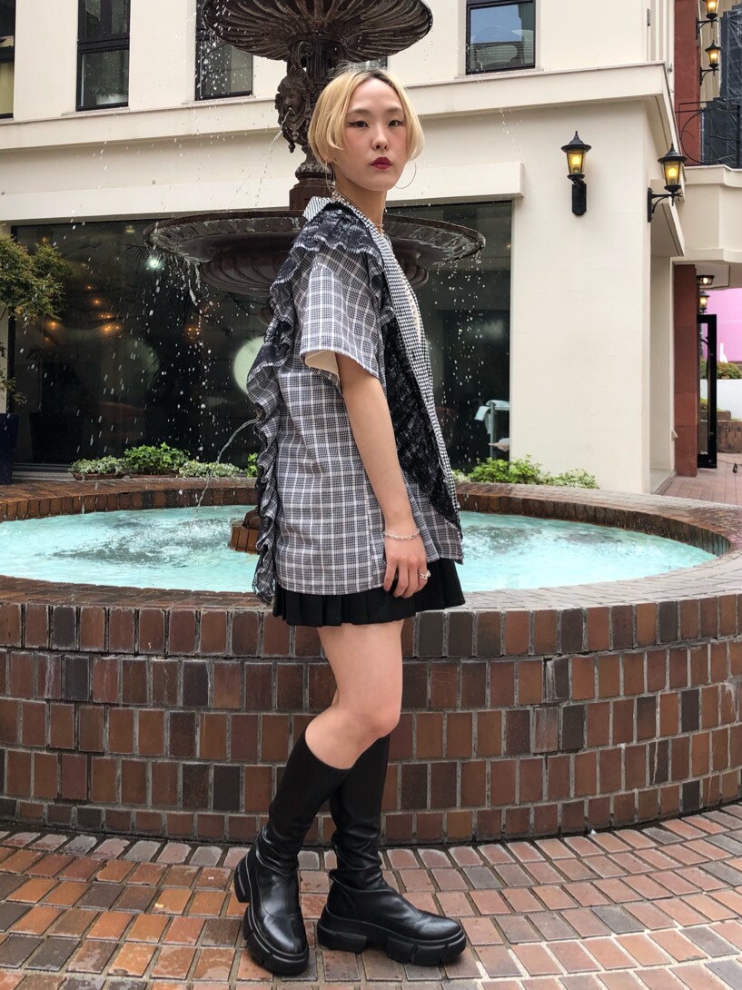 ブラック系のスカート、ブラック系のブーツ、ホワイト系のTシャツ/カットソーを着用したレディースの春コーディネートの3枚目の写真