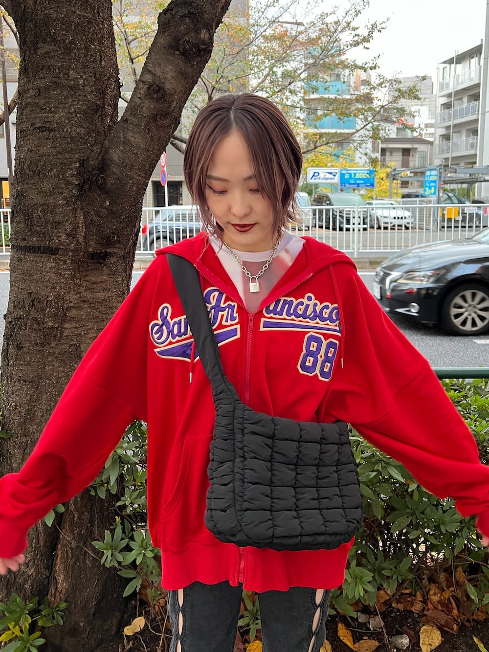レッド系のパーカー、パープル系のTシャツ/カットソー、ブラック系のデニムパンツを着用したレディースの春コーディネートの5枚目の写真