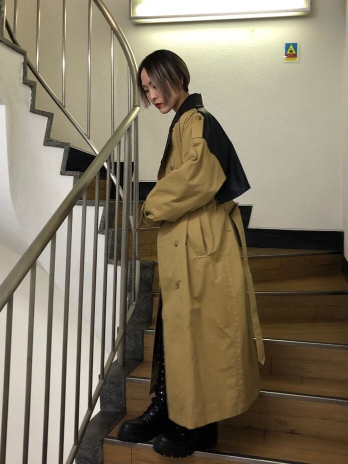 ベージュ系のトレンチコート、ブラック系のその他パンツ、ブラック系のブーツを着用したレディースの春コーディネートの2枚目の写真