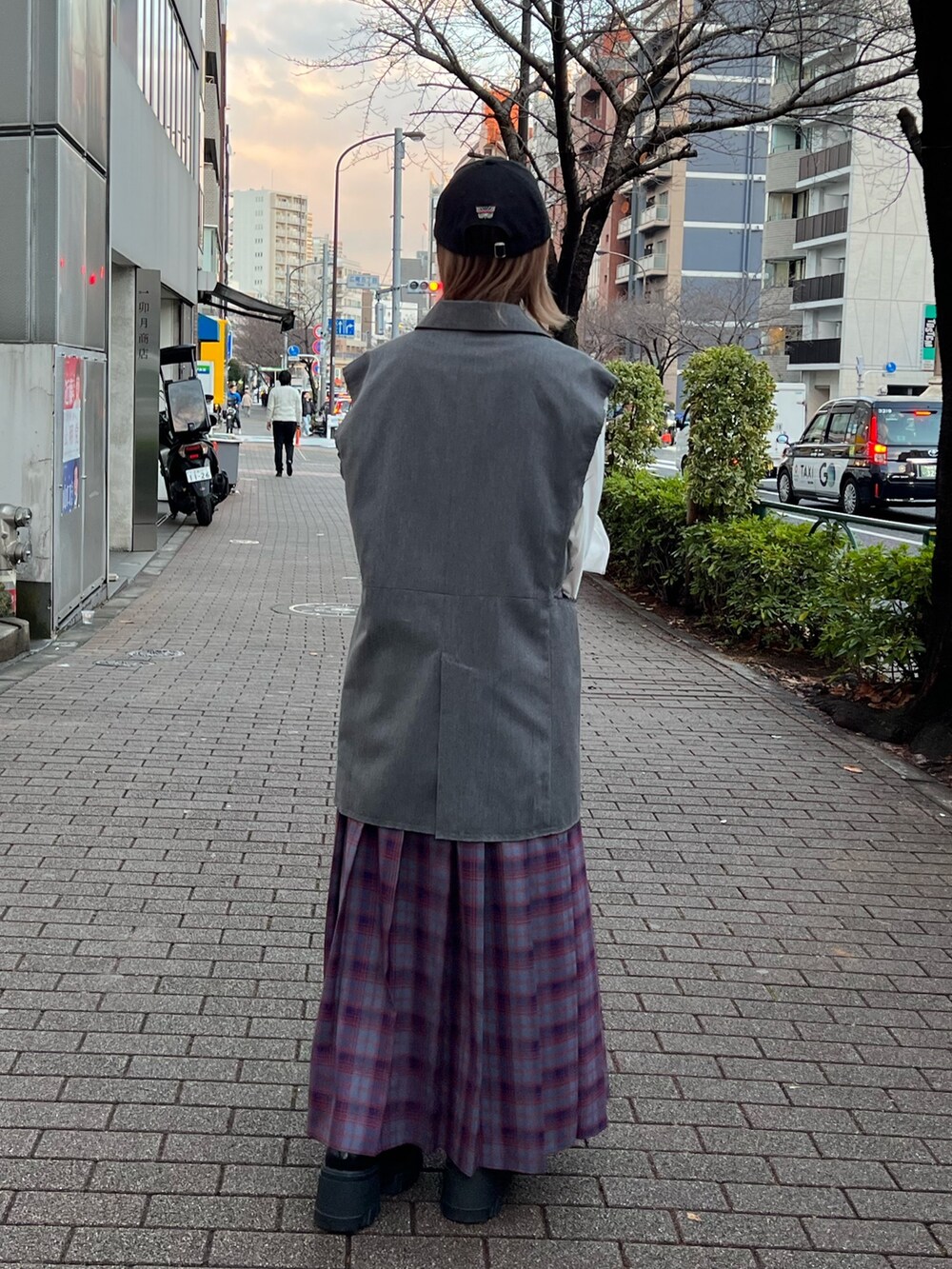 ブルー系のスカート、ホワイト系のTシャツ/カットソー、グレー系のベストを着用したレディースの春コーディネートの2枚目の写真