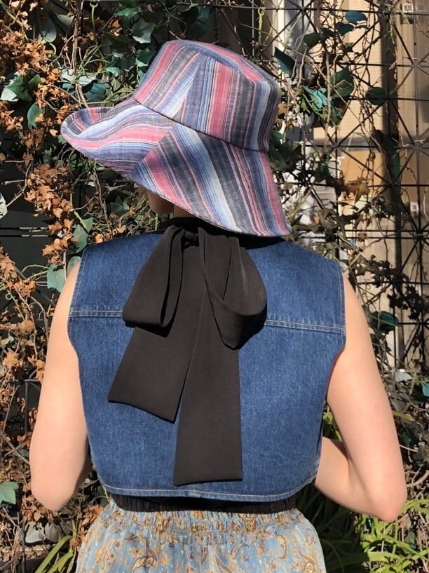 ブルー系のベスト、ブラック系のキャミソール、ホワイト系のボストンバッグを着用したレディースの夏コーディネートの6枚目の写真