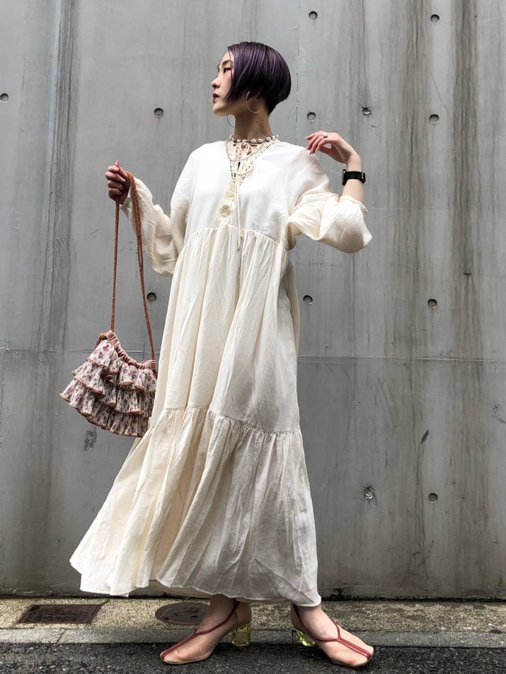 ホワイト系のワンピース、ホワイト系のパンプス、オレンジ系のハンドバッグを着用したレディースの夏コーディネートの2枚目の写真